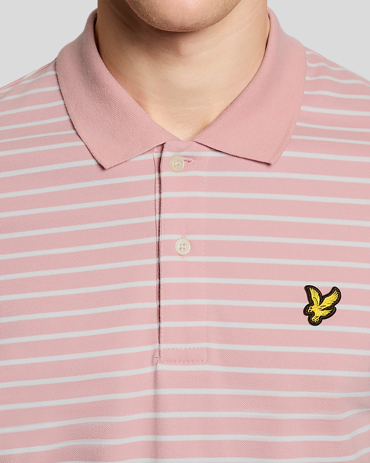 Homme portant un polo breton en piqué rose pamplemousse et blanc
