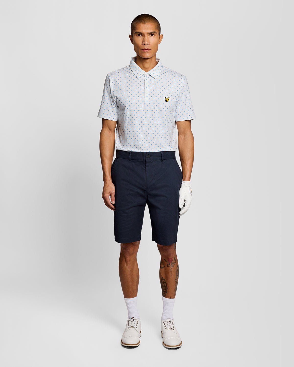Un homme porte un polo blanc à motif croix