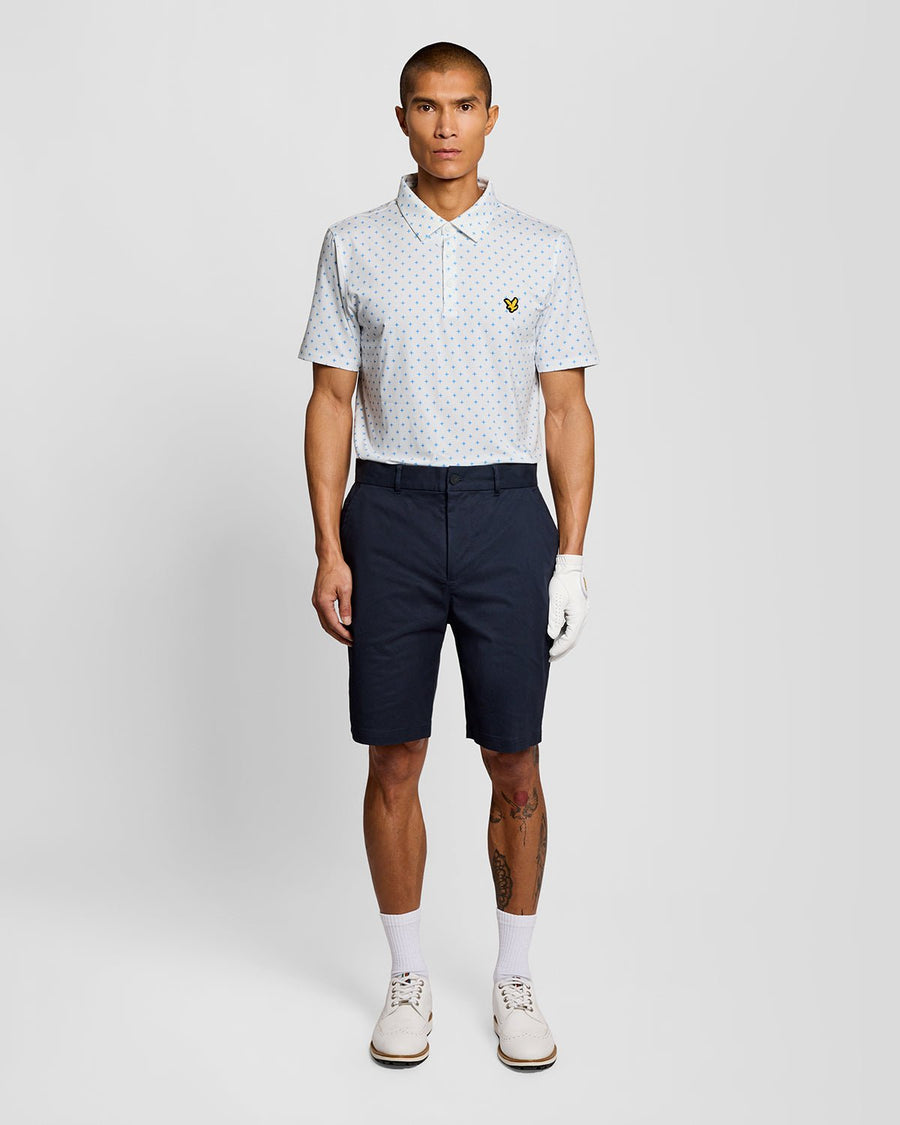 Un homme porte un polo blanc à motif croix
