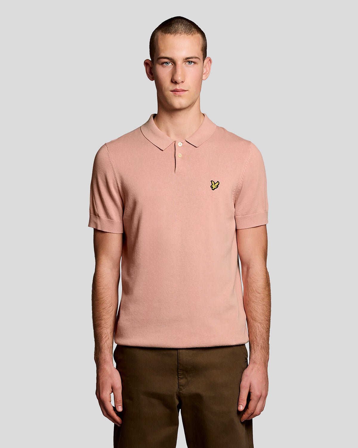 Un homme porte un polo en coton tricoté couleur pamplemousse rose
