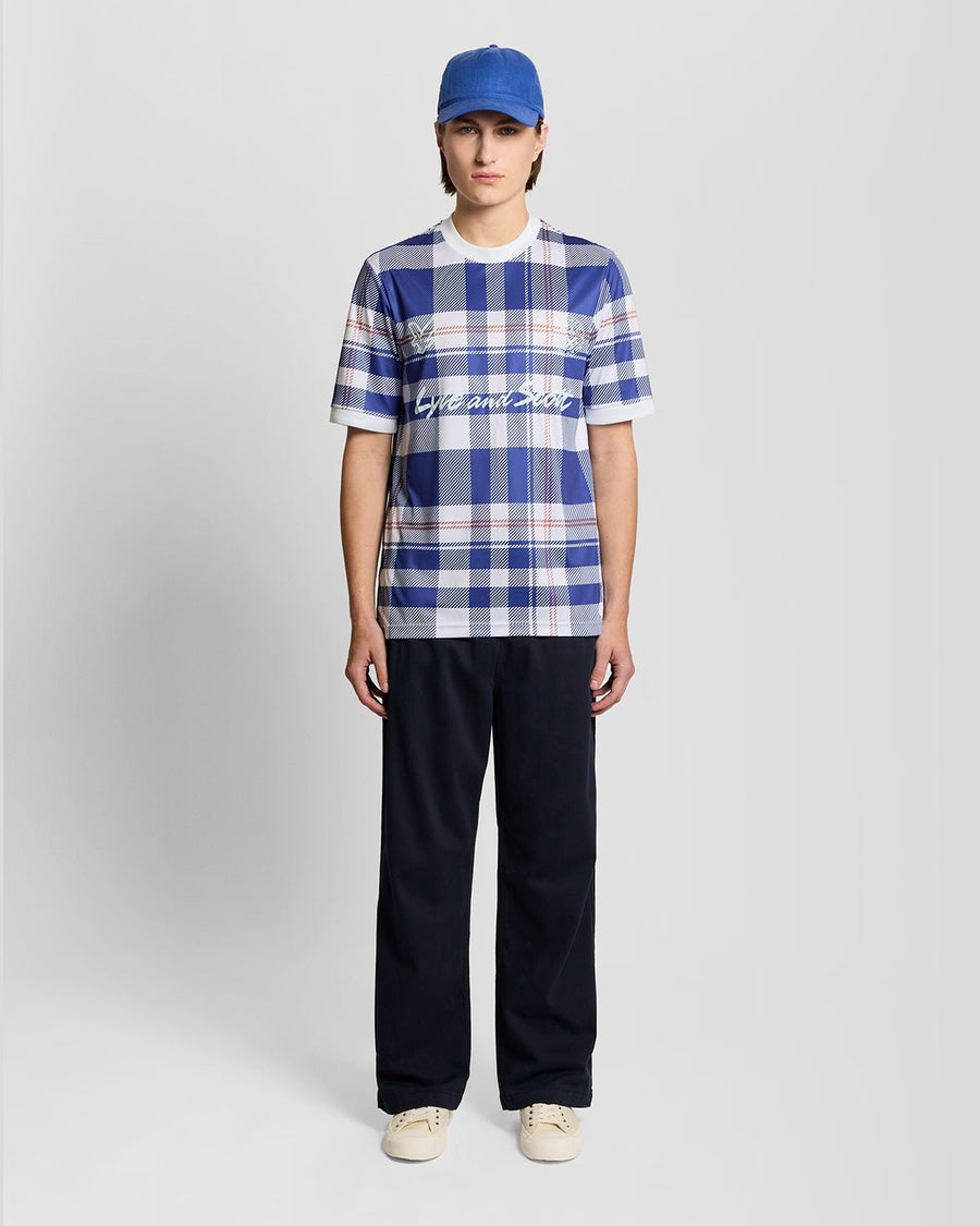 Homme portant un maillot de football à carreaux tartan de style sportif, couleur Now Blue