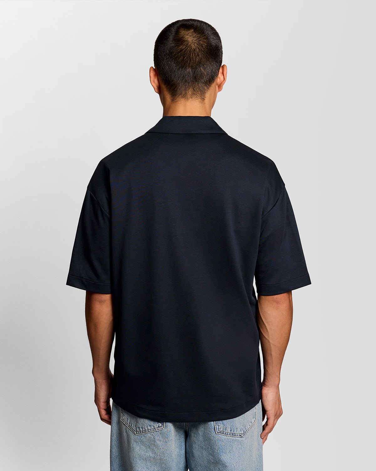 Un homme porte une chemise à manches courtes et col revers, de couleur bleu marine foncé