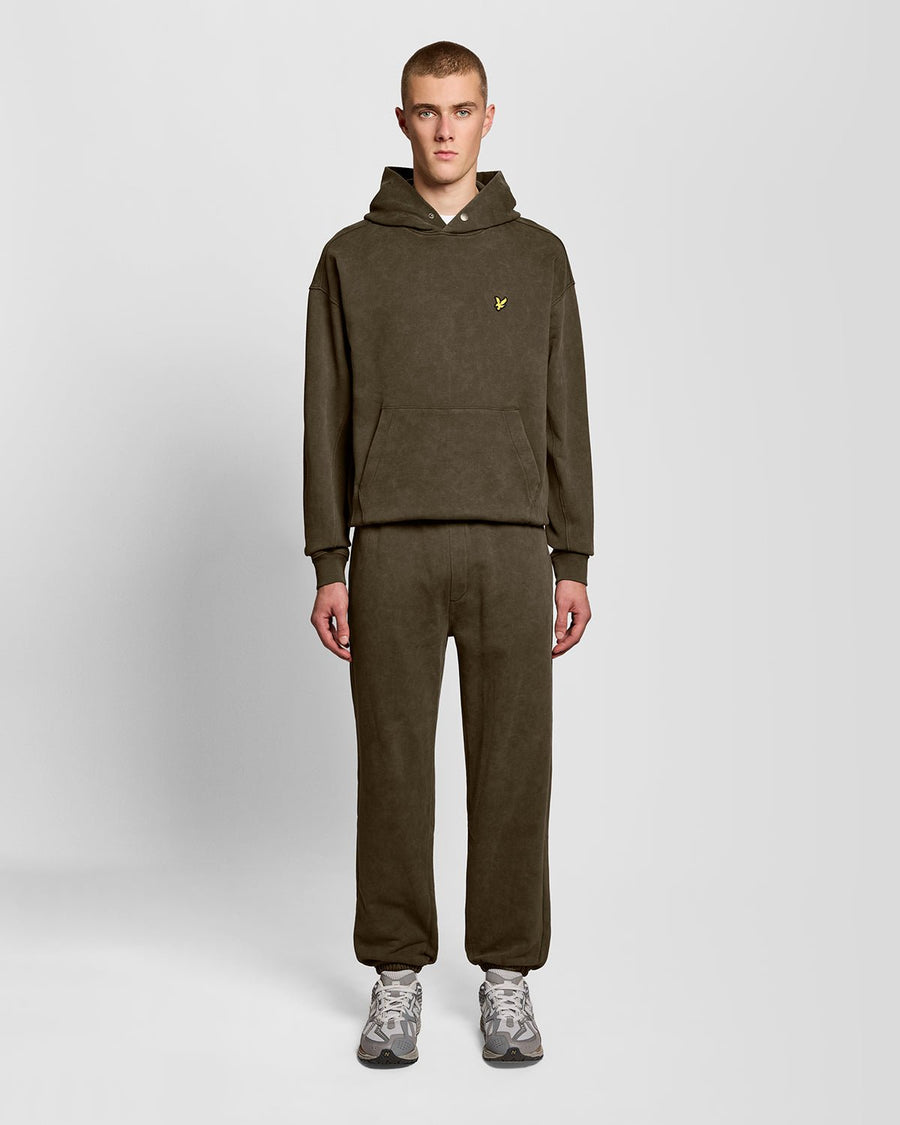 Un homme porte un pantalon de jogging en coton délavé foncé, couleur noir mat