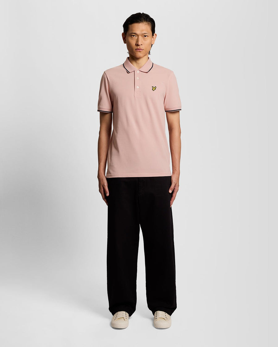 Homme portant un polo à rayures rose pamplemousse et bleu marine foncé