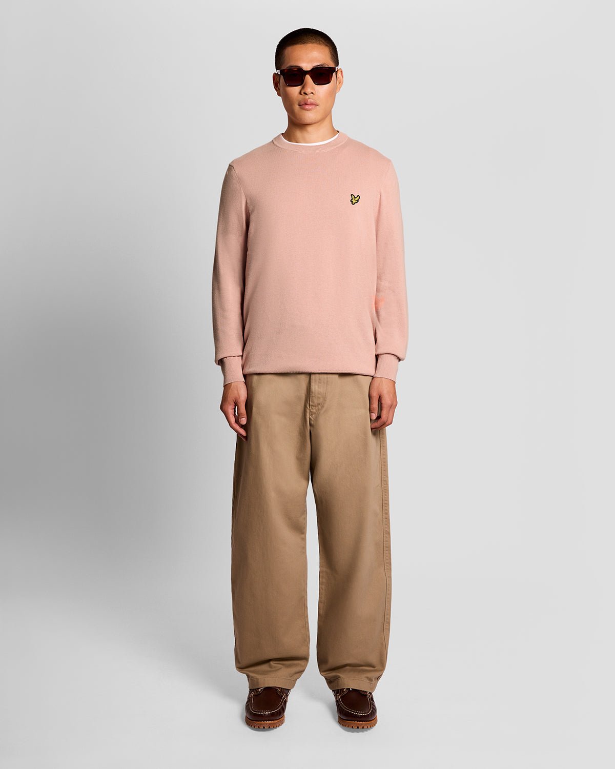 Homme portant un pull à col rond en coton couleur pamplemousse rose