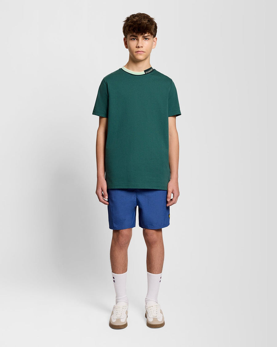 Un homme porte un t-shirt à col relevé avec logo, couleur Everglade