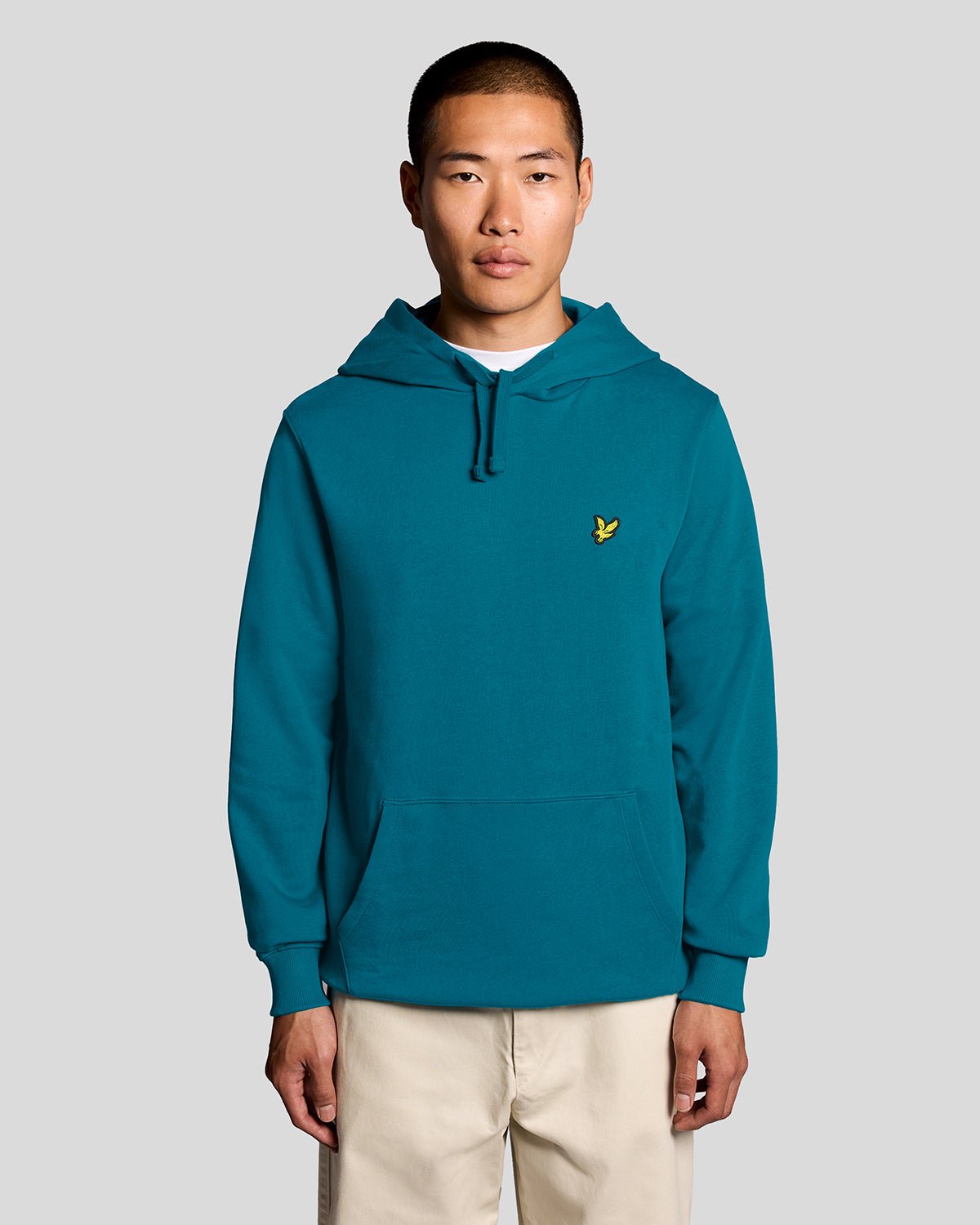 Un homme porte un sweat à capuche en coton Loopback, couleur Lagoon