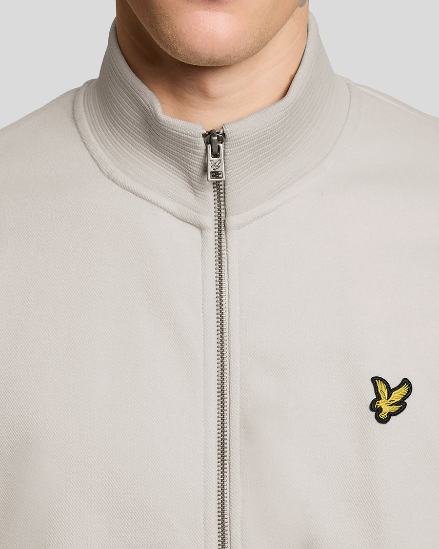 Un homme porte une veste de survêtement en coton mélangé, motif « Pink Tile »