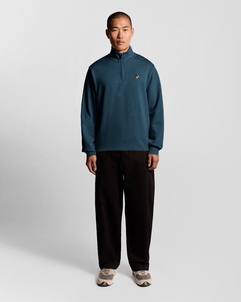 Mann trägt ein „Everyday“ 1/4-Zip-Sweatshirt aus Baumwolle in der Farbe „Rich Teal“