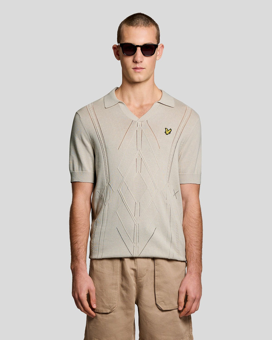 Un homme porte un polo en maille à motif argyle et col ouvert, couleur Cove