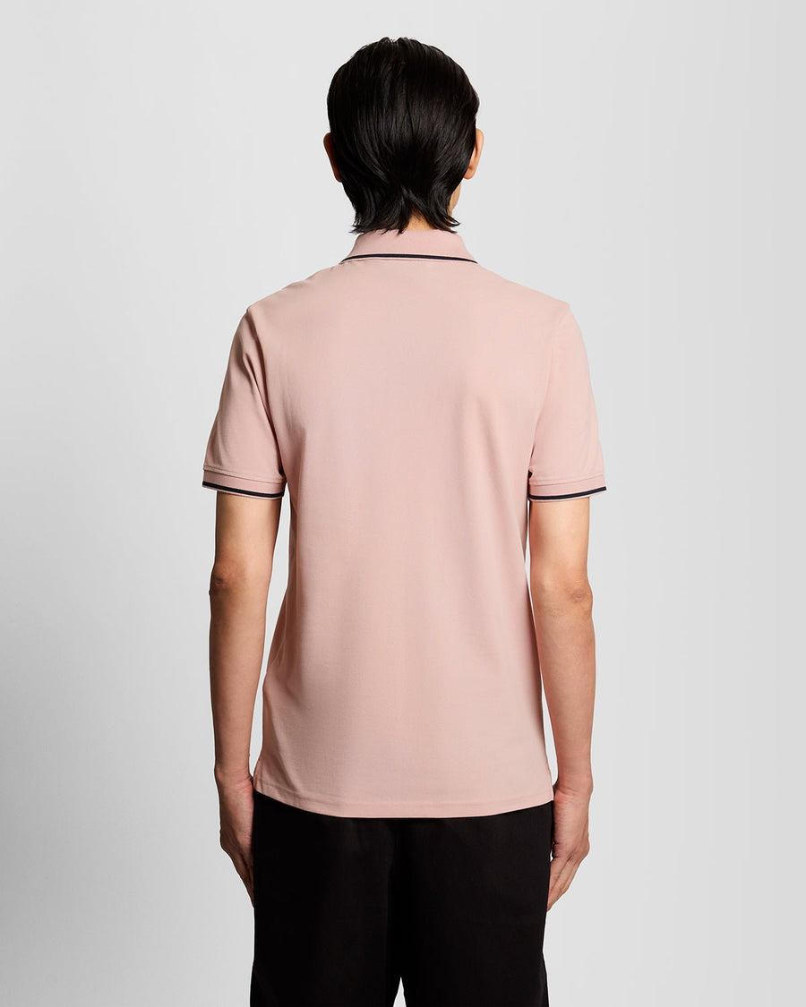 Homme portant un polo à rayures rose pamplemousse et bleu marine foncé