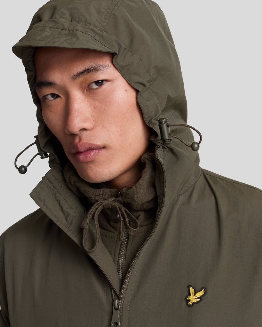 Un homme porte une veste à capuche imperméable de couleur olive