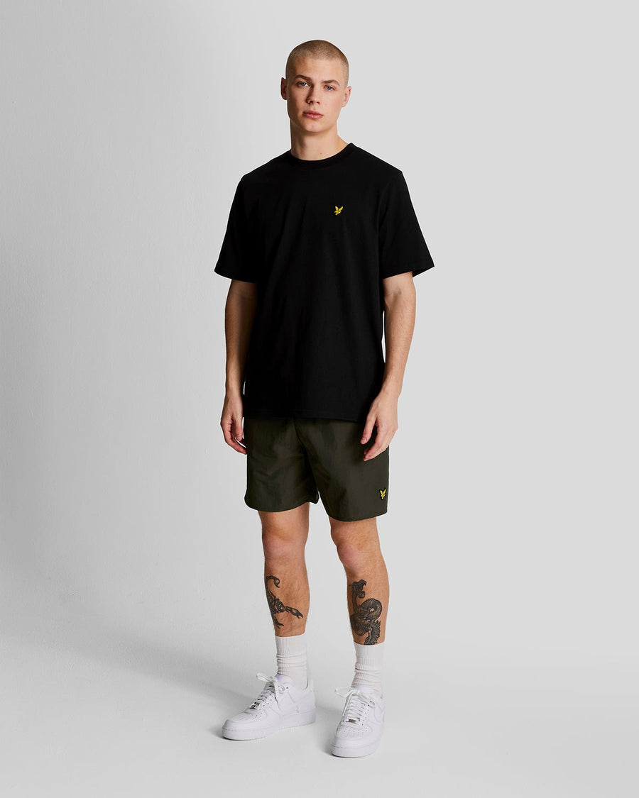Man wears Plain Swim Shorts in Olive