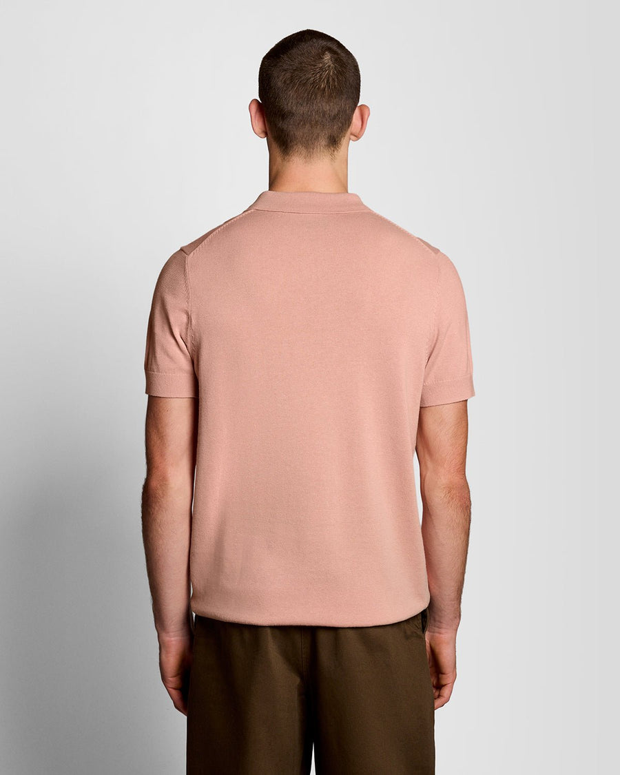 Un homme porte un polo en coton tricoté couleur pamplemousse rose