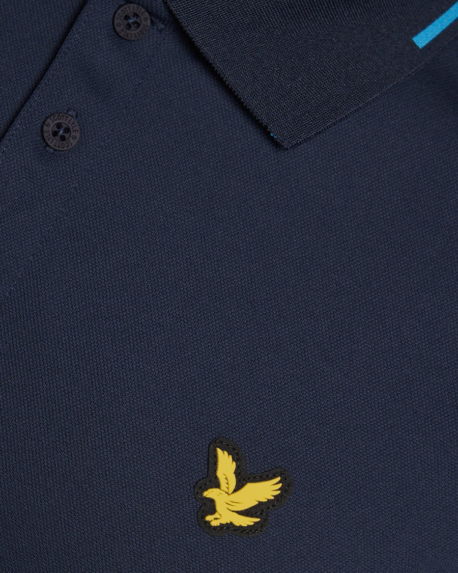 Un homme porte un polo technique à bordures contrastées bleu marine foncé