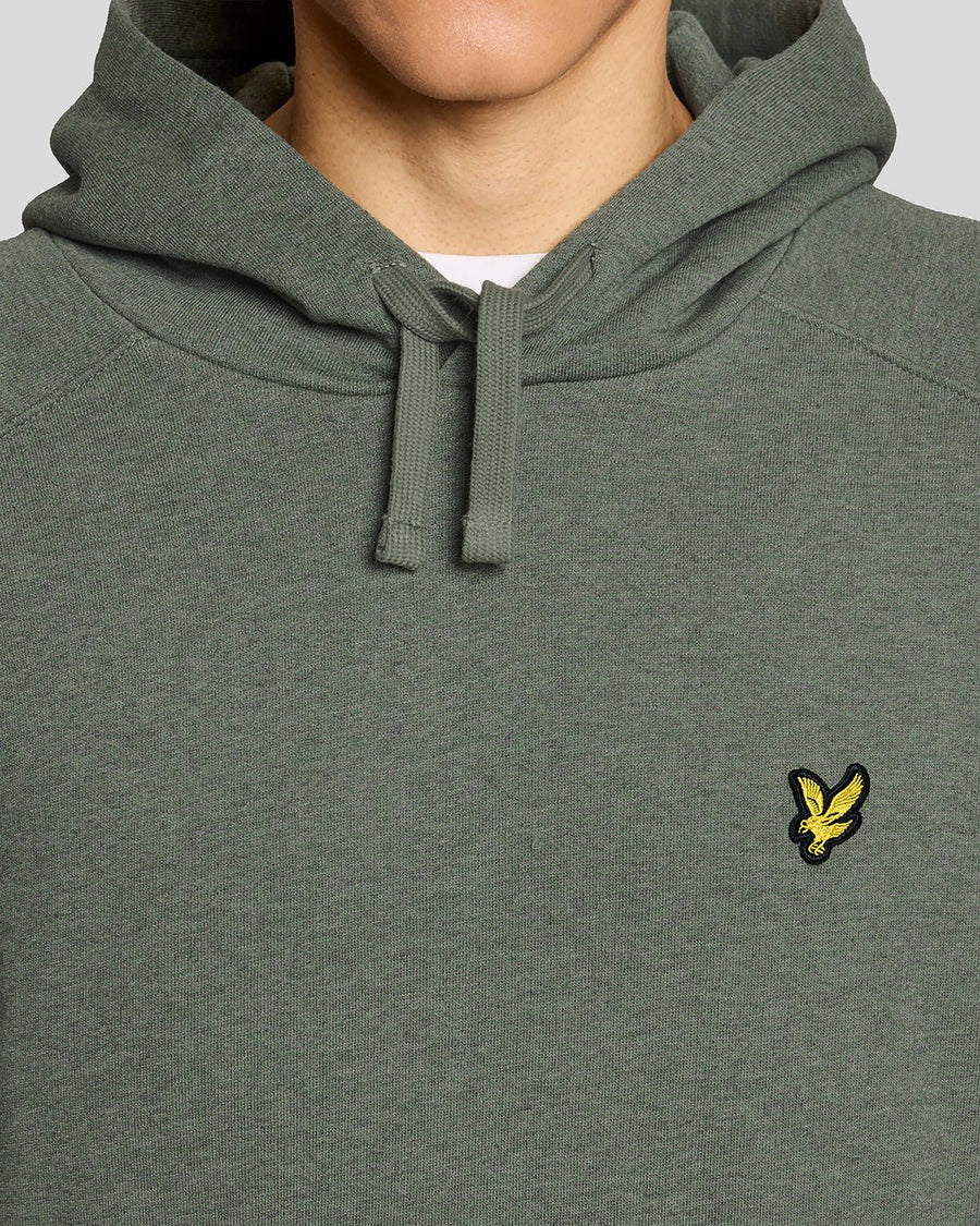 Un homme porte un sweat à capuche raglan en coton chiné, couleur kaki tricolore
