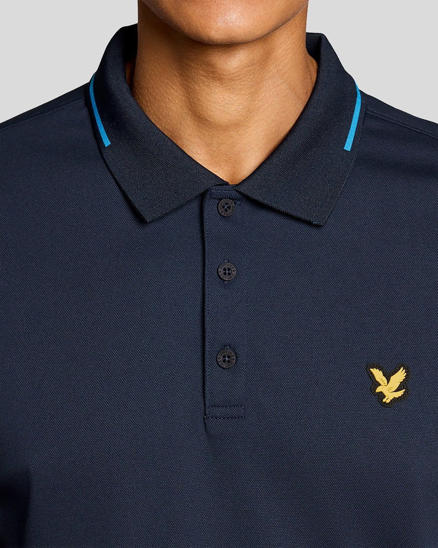 Un homme porte un polo technique à bordures contrastées bleu marine foncé