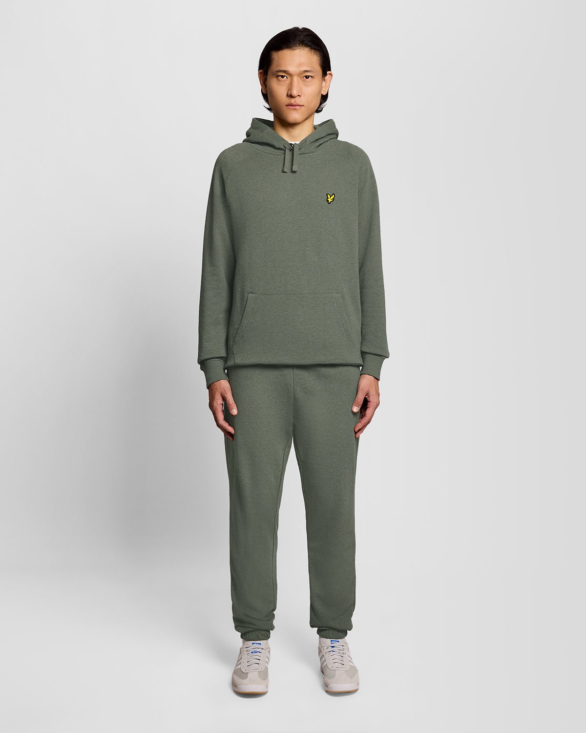 Un homme porte un sweat à capuche raglan en coton chiné, couleur kaki tricolore