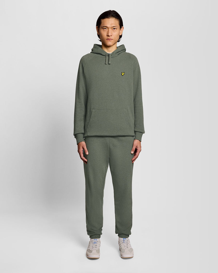 Un homme porte un sweat à capuche raglan en coton chiné, couleur kaki tricolore