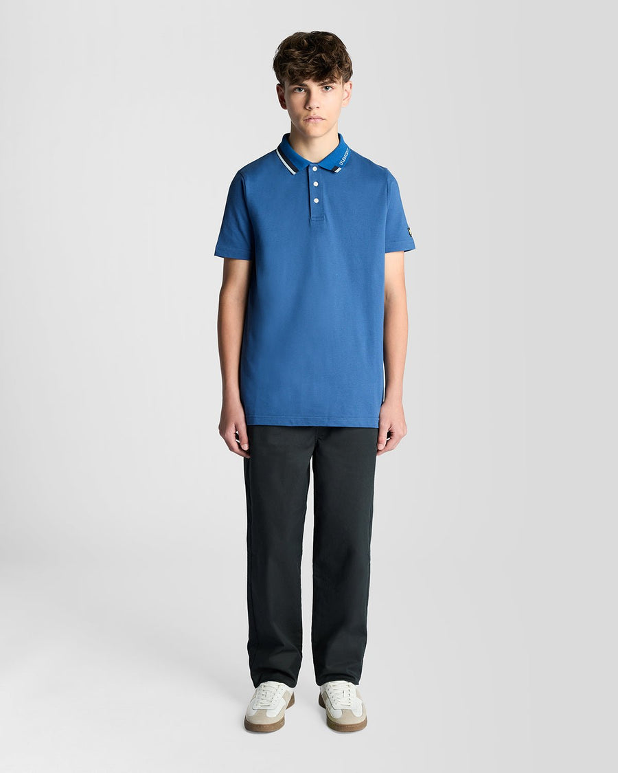 Un homme porte un polo à logo bicolore bleu barbeau foncé