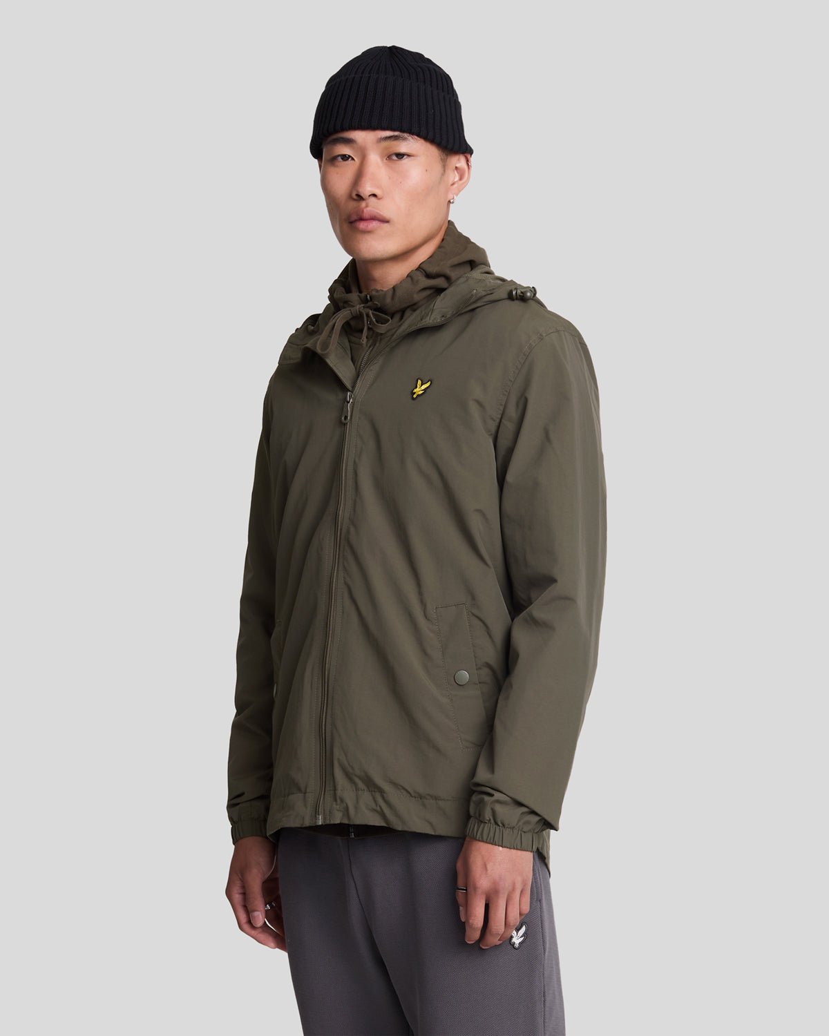 Un homme porte une veste à capuche imperméable de couleur olive
