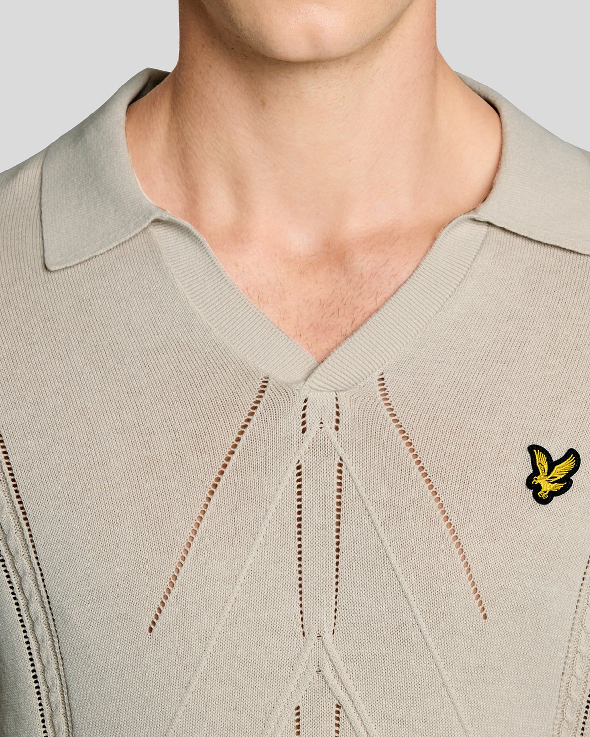Un homme porte un polo en maille à motif argyle et col ouvert, couleur Cove