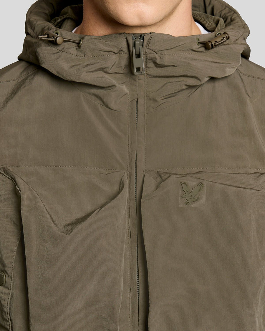 Un homme porte une veste coupe-vent légère de couleur kaki cendré