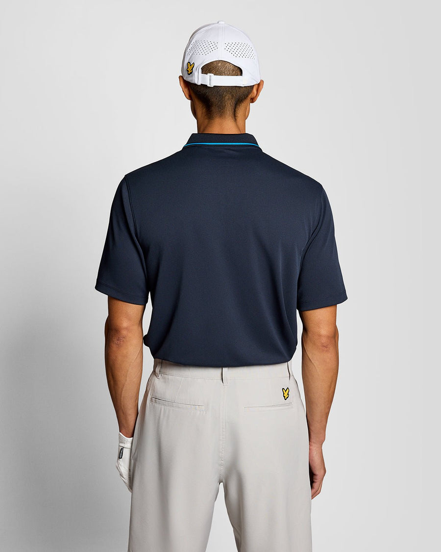 Un homme porte un polo technique à bordures contrastées bleu marine foncé
