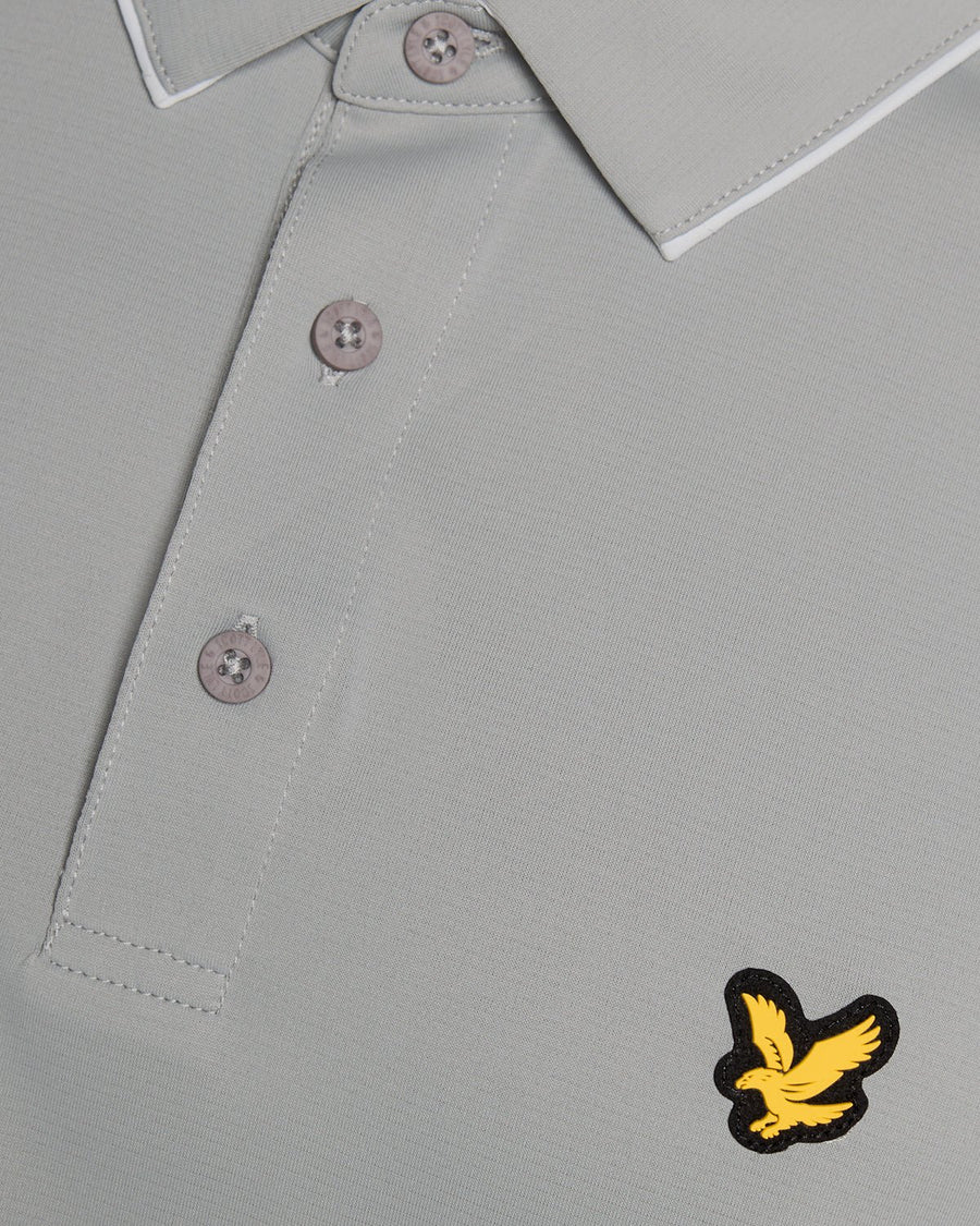 Un homme porte un polo à col contrasté de couleur « Ultimate Grey »