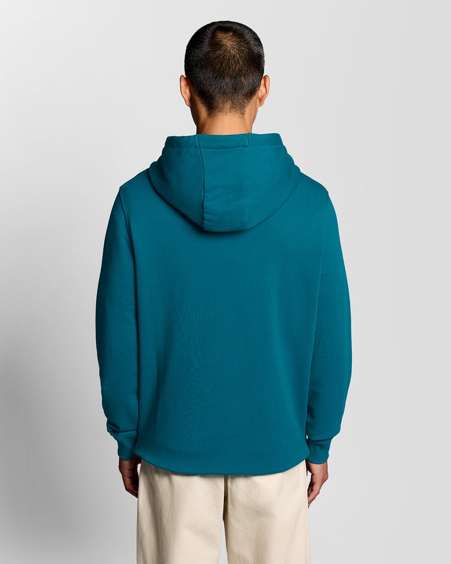 Un homme porte un sweat à capuche en coton Loopback, couleur Lagoon