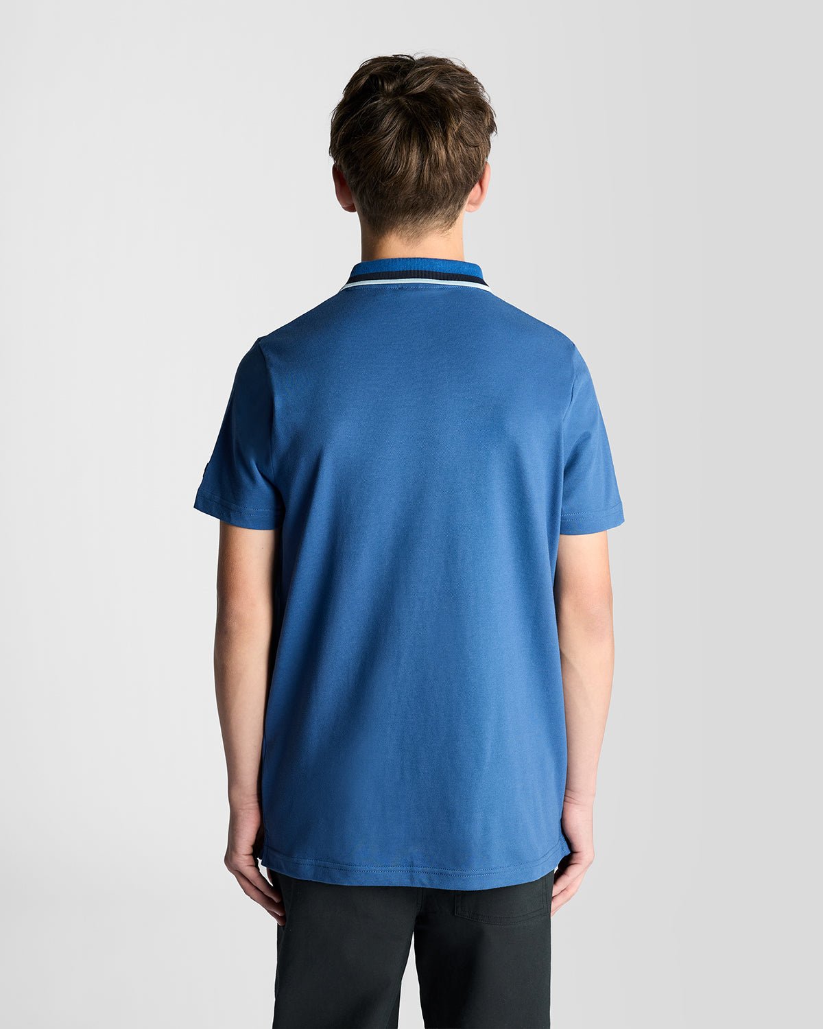 Un homme porte un polo à logo bicolore bleu barbeau foncé