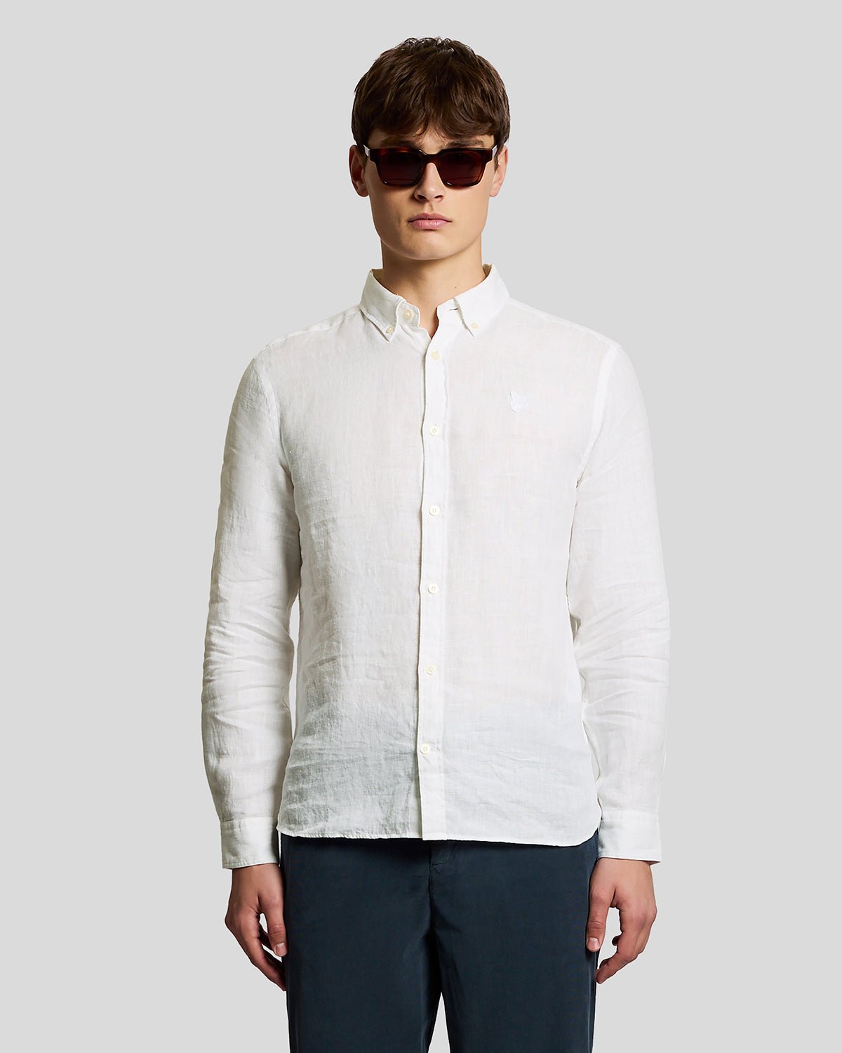 Un homme porte une chemise en lin boutonnée, de couleur blanche