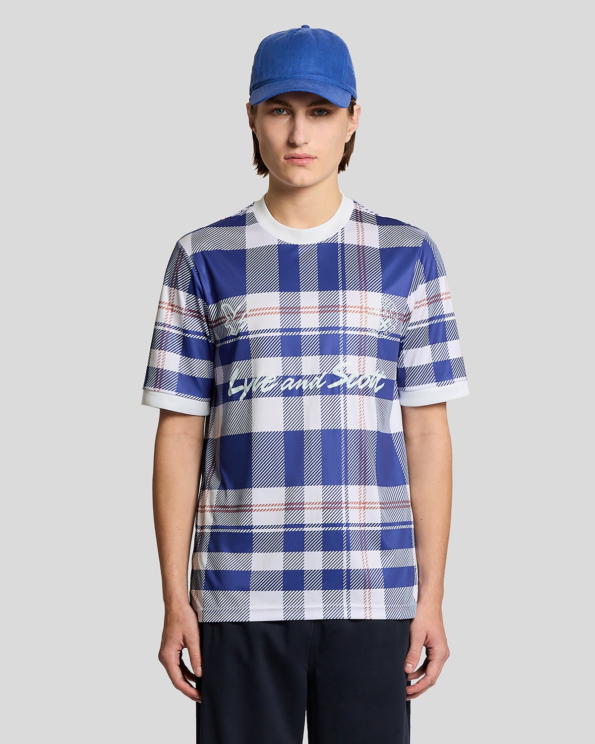 Homme portant un maillot de football à carreaux tartan de style sportif, couleur Now Blue