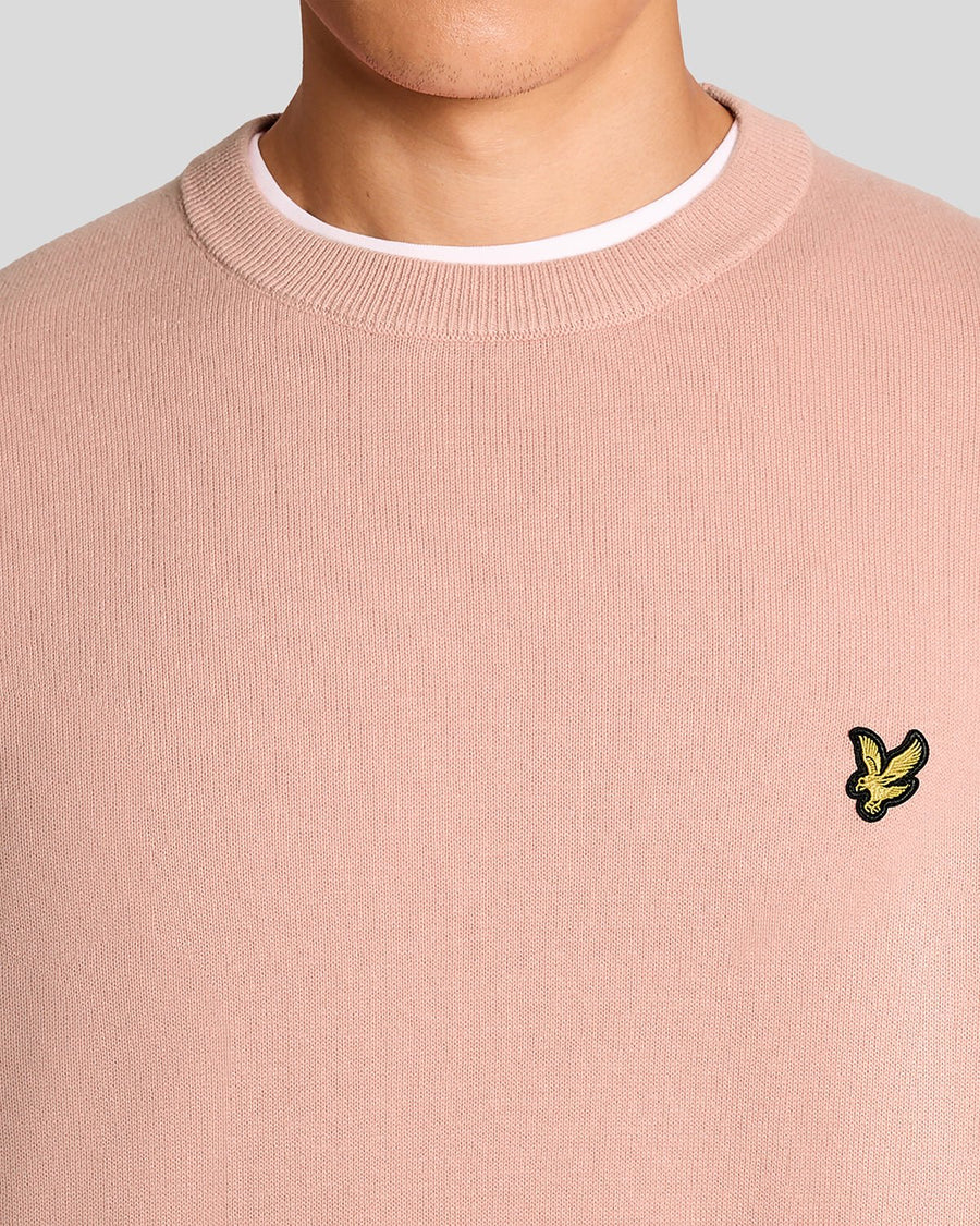Homme portant un pull à col rond en coton couleur pamplemousse rose
