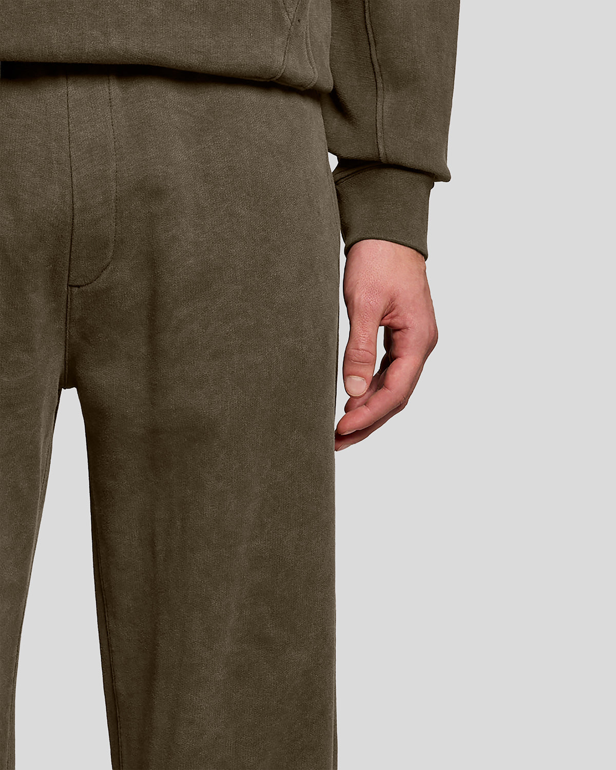 Un homme porte un pantalon de jogging en coton délavé foncé, couleur noir mat