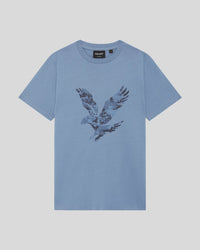 Junge trägt ein T-Shirt mit pixeliger Adlergrafik in der Farbe „Power Blue“