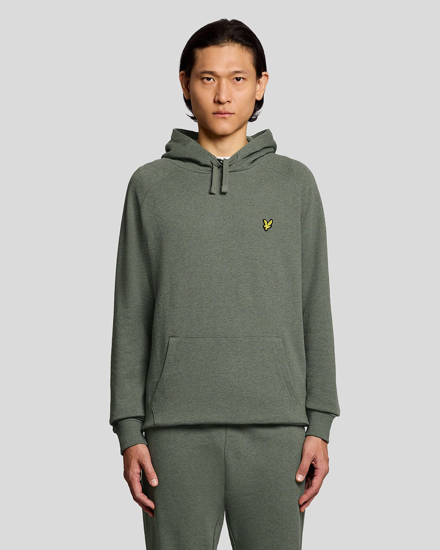Un homme porte un sweat à capuche raglan en coton chiné, couleur kaki tricolore