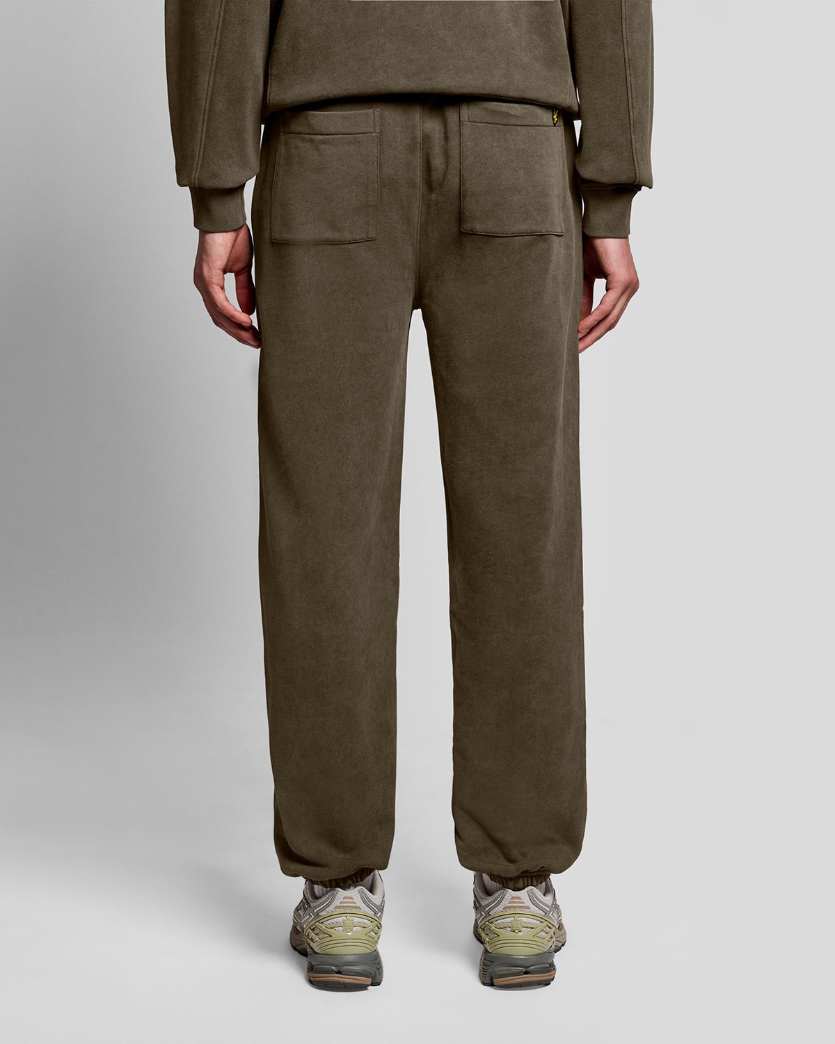 Un homme porte un pantalon de jogging en coton délavé foncé, couleur noir mat