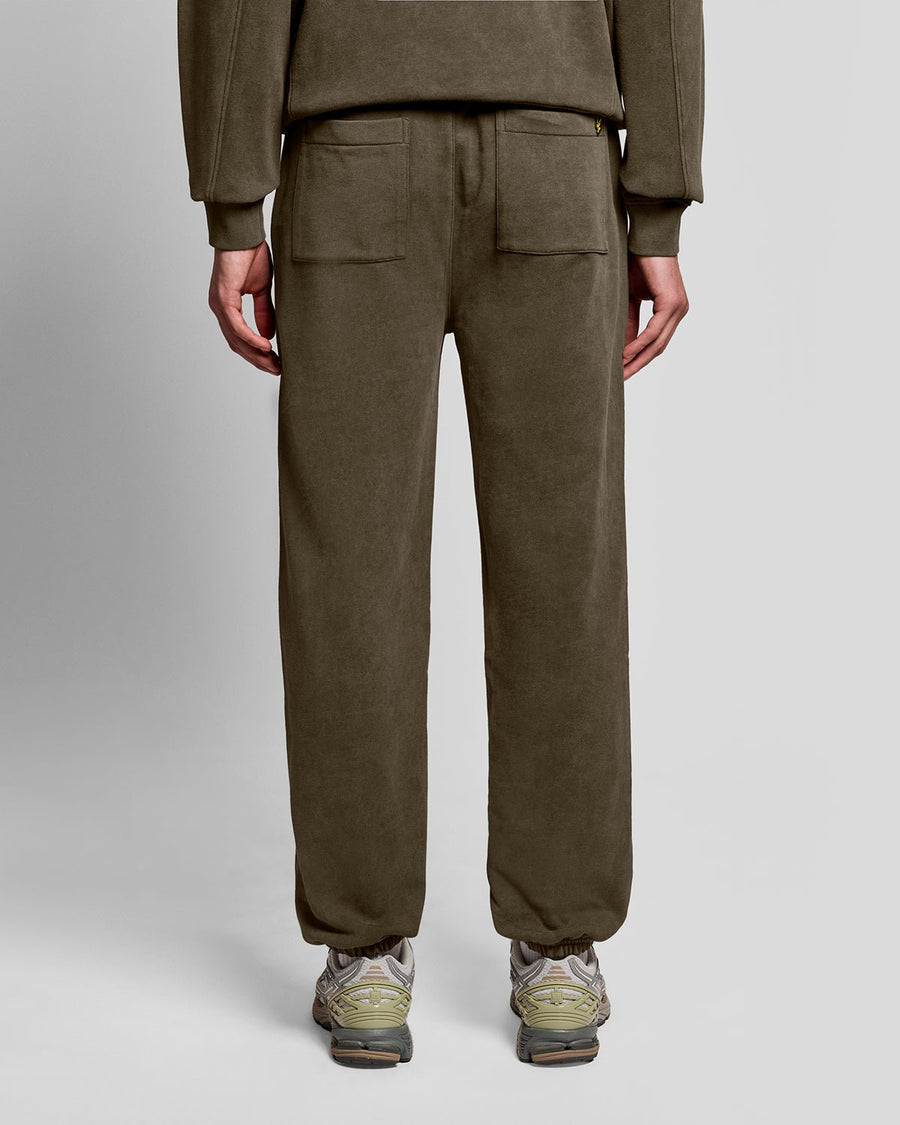 Un homme porte un pantalon de jogging en coton délavé foncé, couleur noir mat
