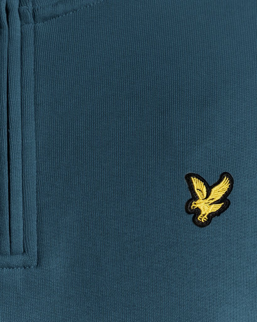 Mann trägt ein „Everyday“ 1/4-Zip-Sweatshirt aus Baumwolle in der Farbe „Rich Teal“