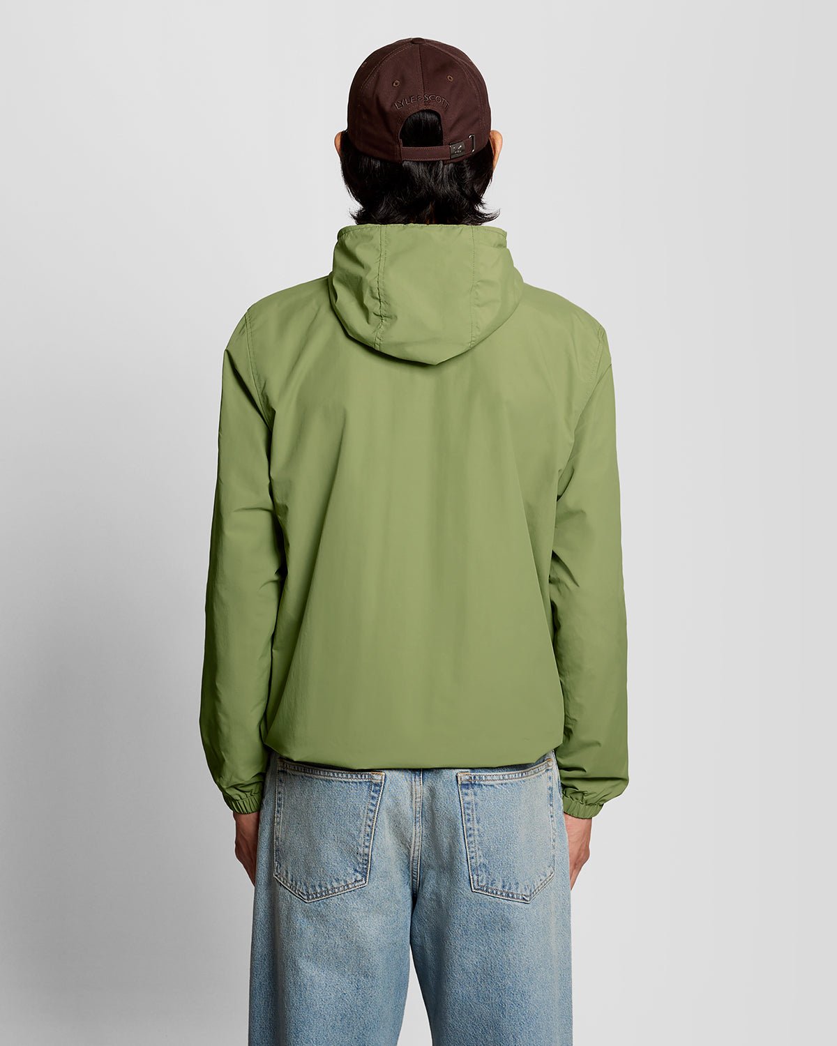 Uomo con giacca con cappuccio resistente all'acqua in verde arbusto