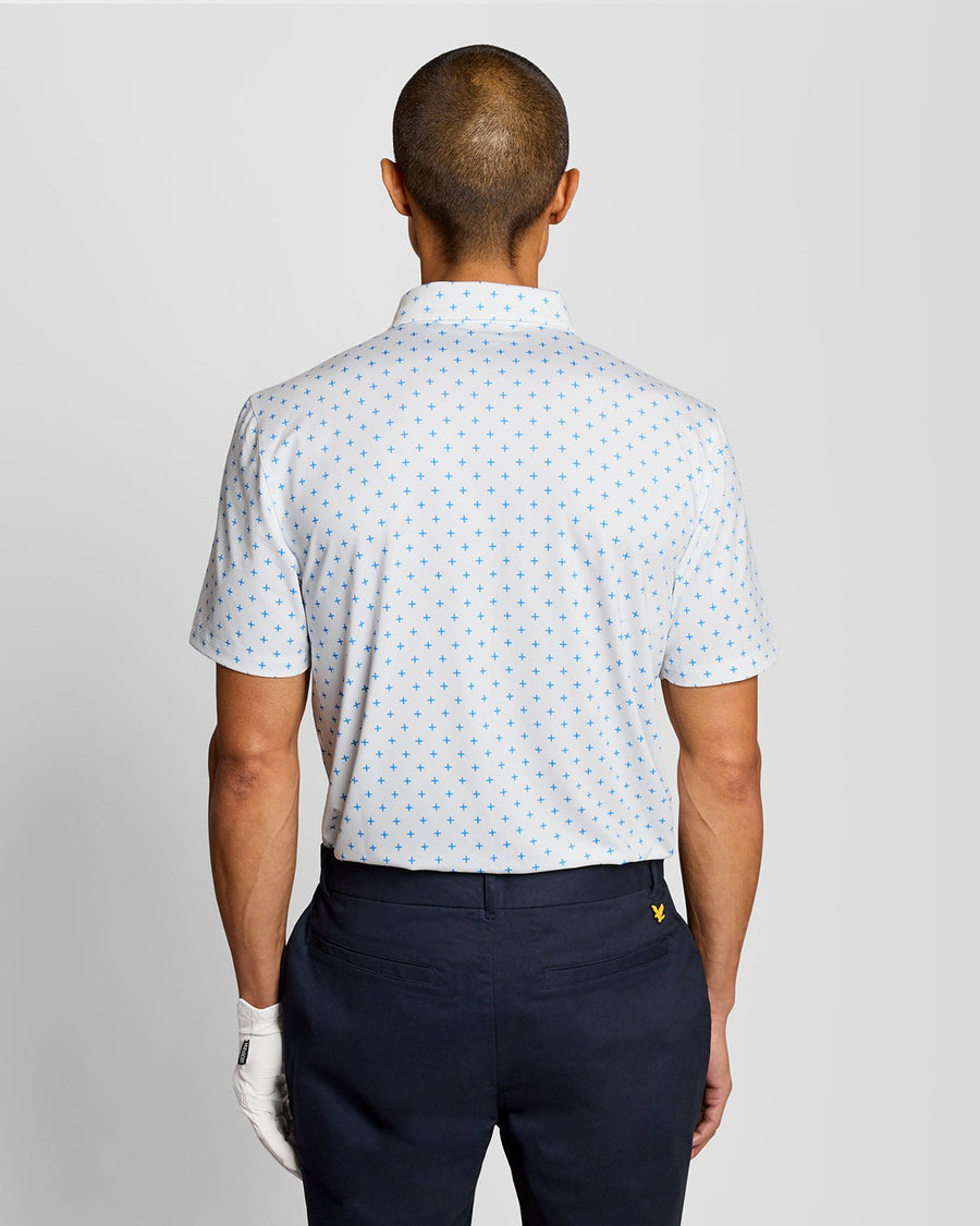 Un homme porte un polo blanc à motif croix
