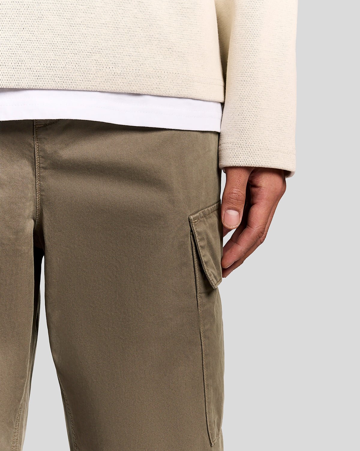 Un homme porte un pantalon cargo à revers de couleur kaki cendré