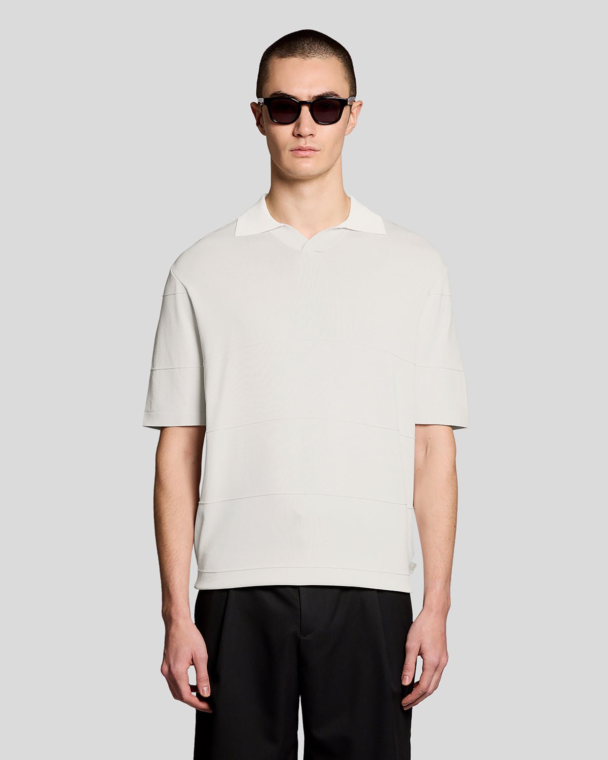 Un homme porte un polo en maille fine à col ouvert, couleur Skylight