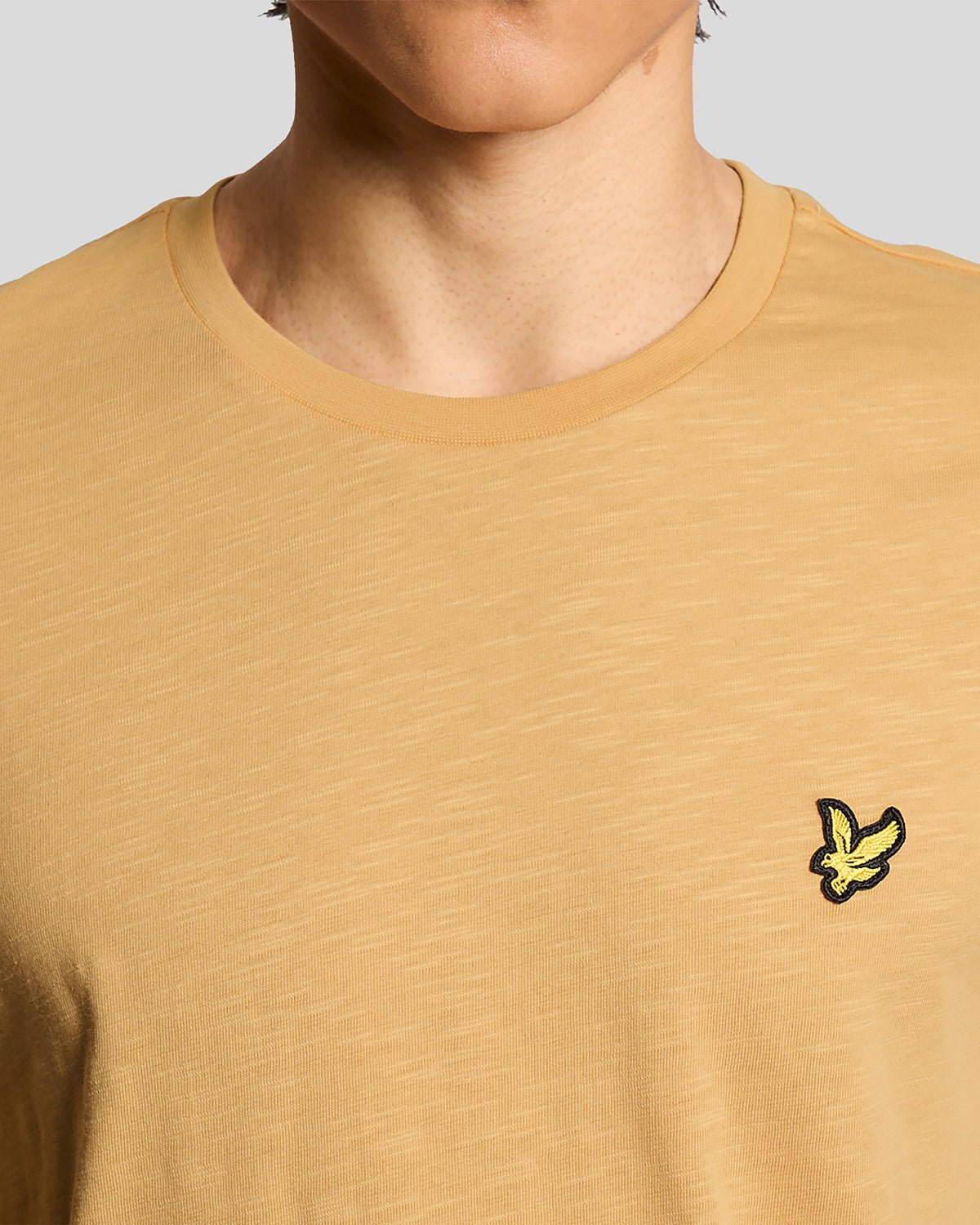 Un homme porte un t-shirt en coton fin texturé, motif nid d'abeille
