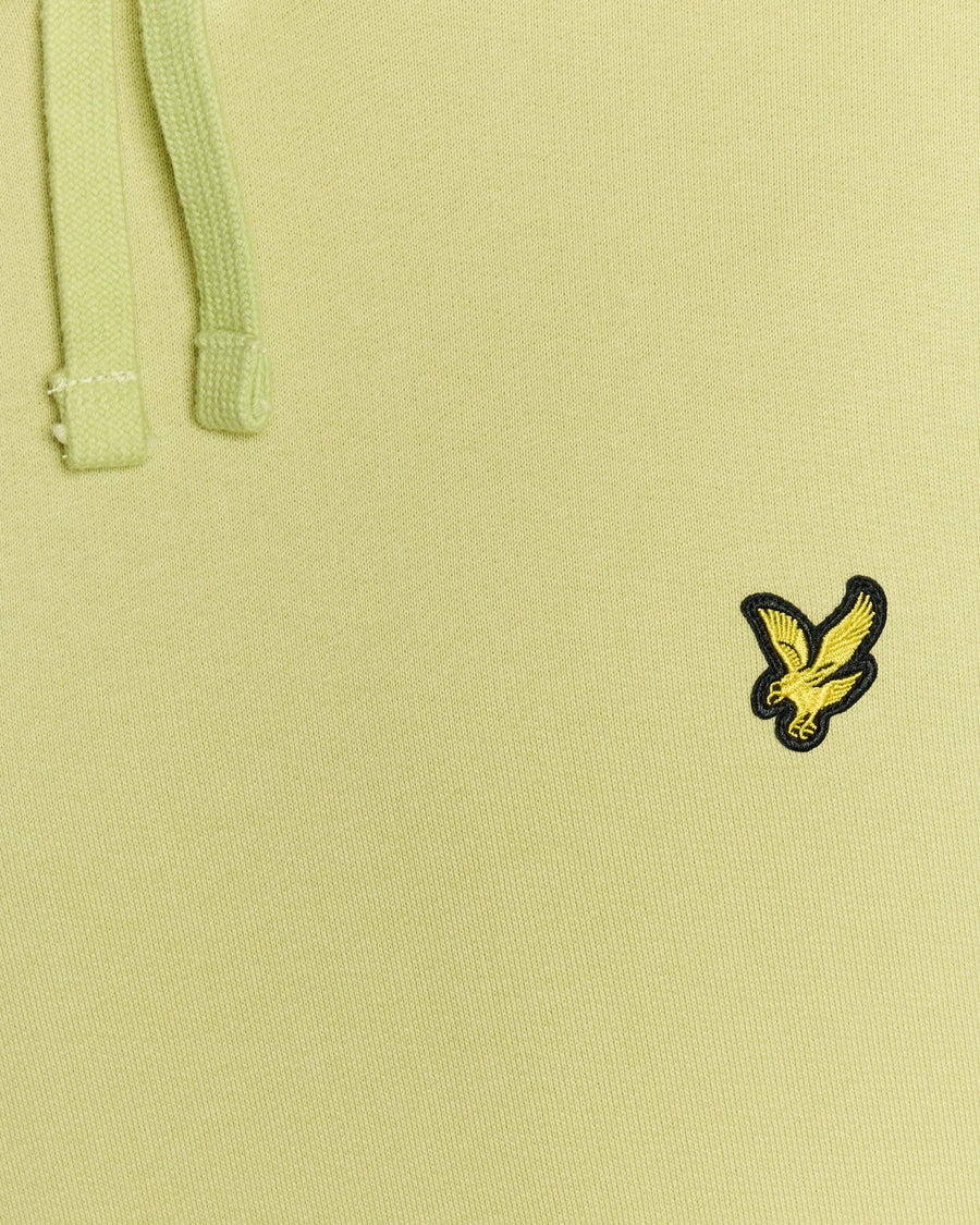 Un homme porte un sweat à capuche Loopback en coton, couleur « Green Grass »