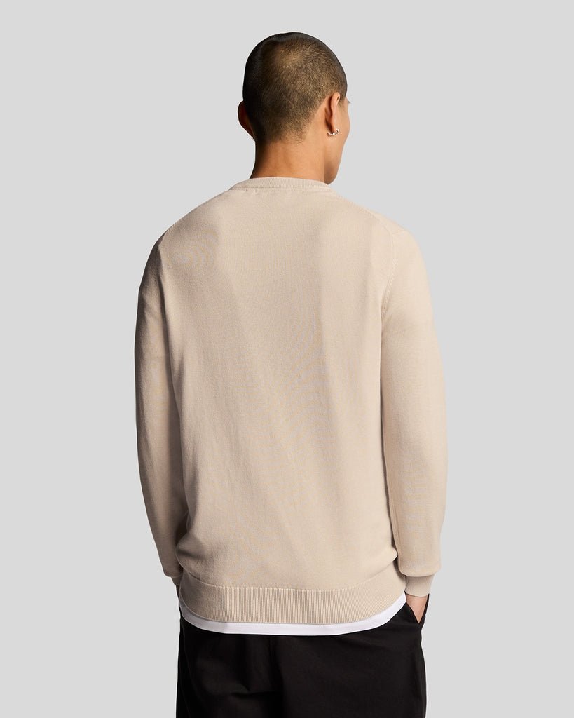 Un homme porte un pull à col rond en coton, couleur Cove
