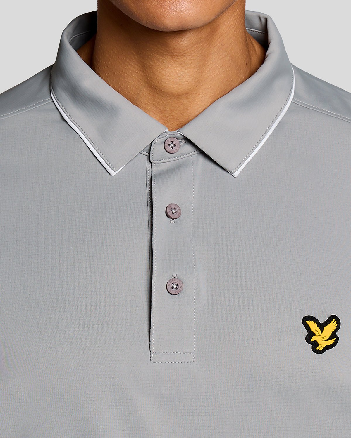 Un homme porte un polo à col contrasté de couleur « Ultimate Grey »