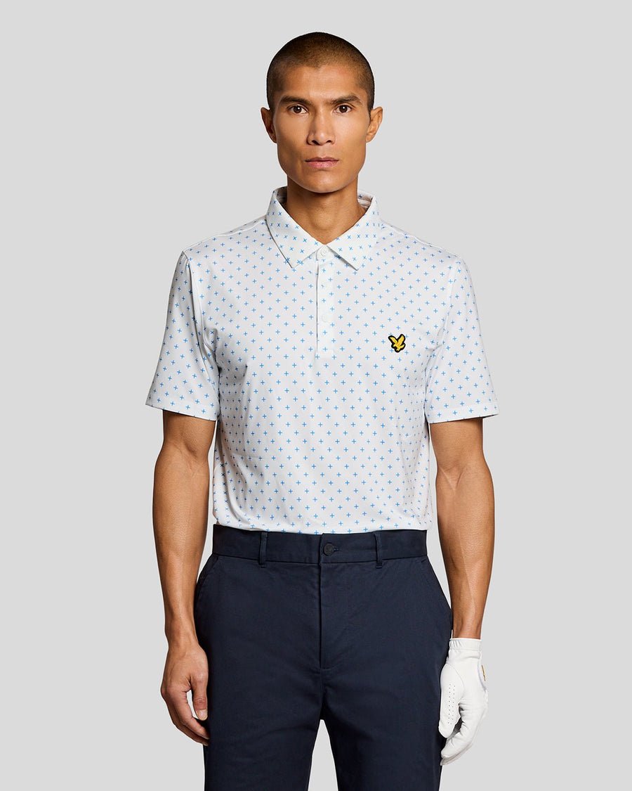 Un homme porte un polo blanc à motif croix