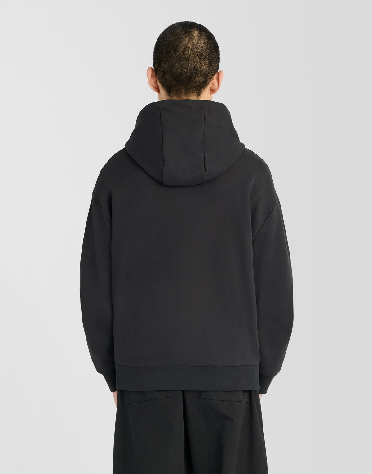 Man wears Heavyweight Loopback Zip Hoodie in Jet Black